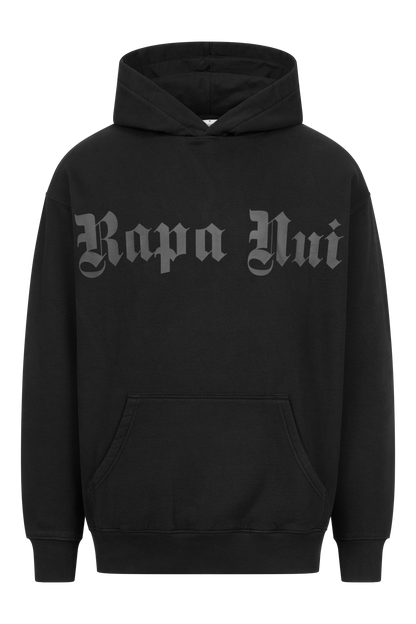 Ein schwarzer OVERSIZE-HOODIE mit PRINT und dem Text „Rapa Nui“ in fetter, altenglischer Schrift auf der Brust. Der RAPANUI ORIGINAL-Hoodie, zertifiziert nach Control Union CU 833078, hat eine Beuteltasche auf der Vorderseite und eine verstellbare Kapuze mit Kordelzug.