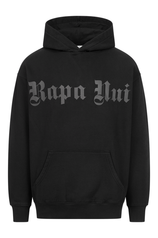 Ein schwarzer OVERSIZE-HOODIE mit PRINT und dem Text „Rapa Nui“ in fetter, altenglischer Schrift auf der Brust. Der RAPANUI ORIGINAL-Hoodie, zertifiziert nach Control Union CU 833078, hat eine Beuteltasche auf der Vorderseite und eine verstellbare Kapuze mit Kordelzug.